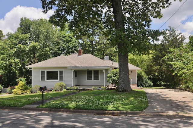  - view of front of house with a chimney, a front yard, and concrete driveway