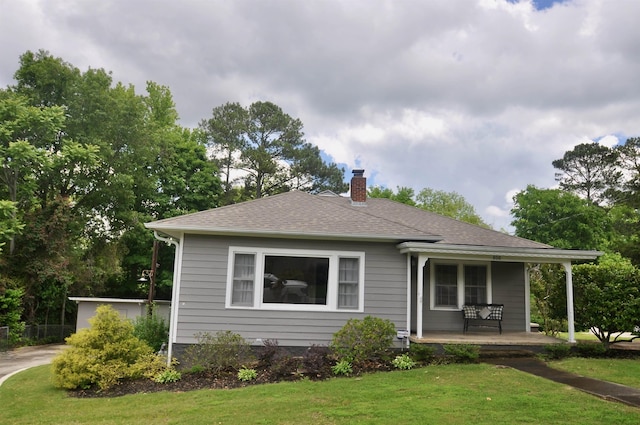  - bungalow-style house with a porch, a chimney, a front lawn, and roof with shingles