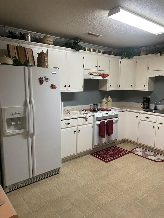 kitchen with a textured ceiling, white cabinets, white appliances, and sink