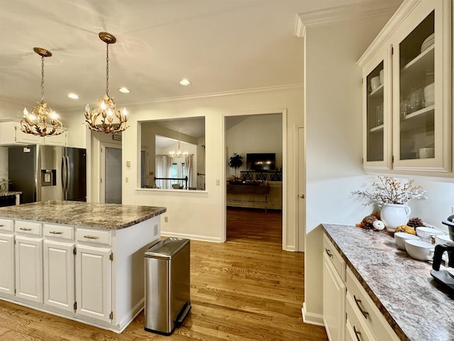 kitchen featuring stainless steel fridge with ice dispenser, light wood-type flooring, white cabinetry, and hanging light fixtures