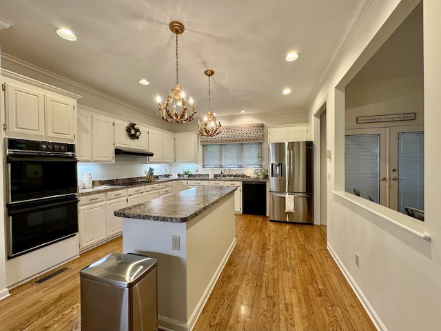 kitchen featuring black appliances, sink, decorative light fixtures, a kitchen island, and white cabinetry