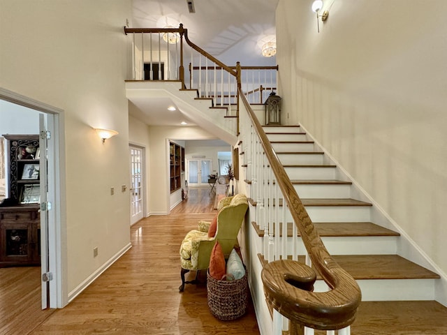 stairway featuring a towering ceiling and wood-type flooring