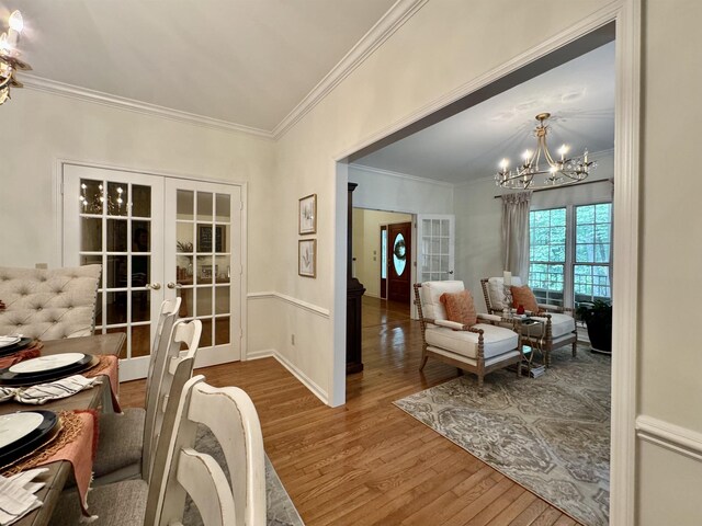 dining room featuring hardwood / wood-style flooring, a chandelier, crown molding, and french doors