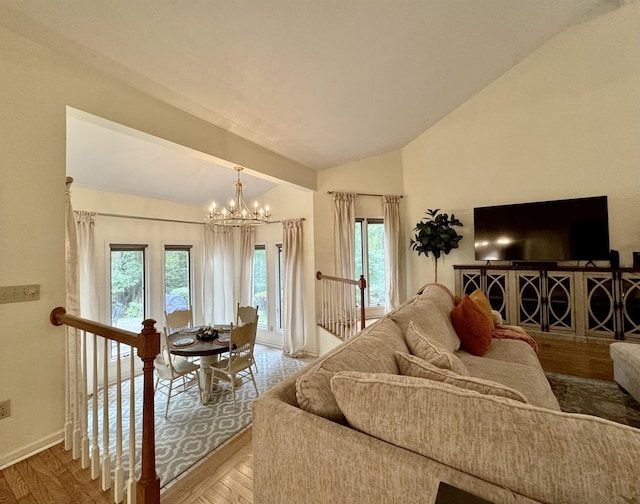 living room with hardwood / wood-style flooring, lofted ceiling, and an inviting chandelier