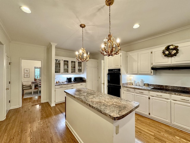 kitchen with white cabinets, light hardwood / wood-style floors, a kitchen island, and black appliances