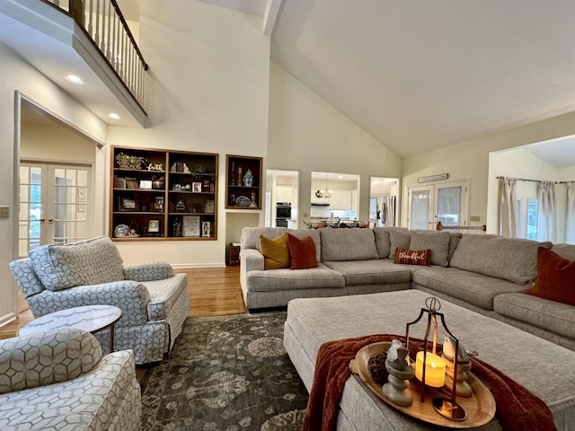 living room with wood-type flooring, high vaulted ceiling, and french doors