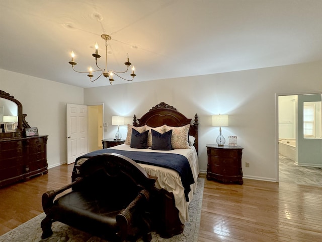 bedroom with ensuite bath, wood-type flooring, and an inviting chandelier