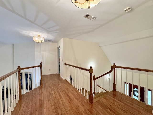 stairs featuring a notable chandelier, wood-type flooring, and lofted ceiling