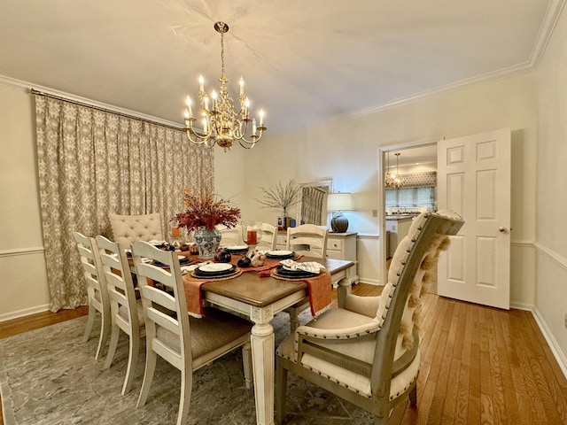 dining room with light hardwood / wood-style flooring, ornamental molding, and a notable chandelier