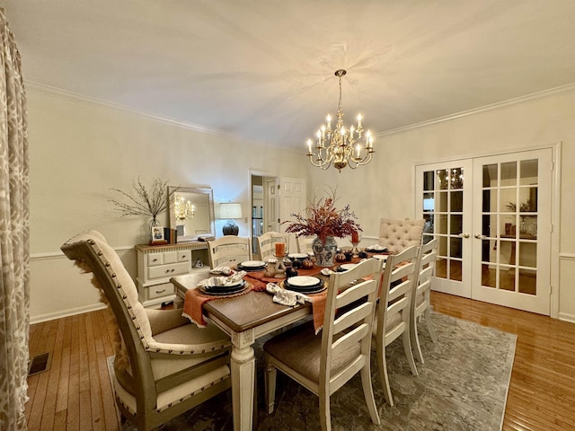 dining room featuring hardwood / wood-style flooring, an inviting chandelier, ornamental molding, and french doors