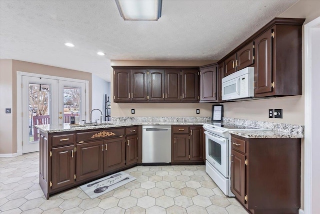 kitchen with dark brown cabinetry, sink, white appliances, and kitchen peninsula