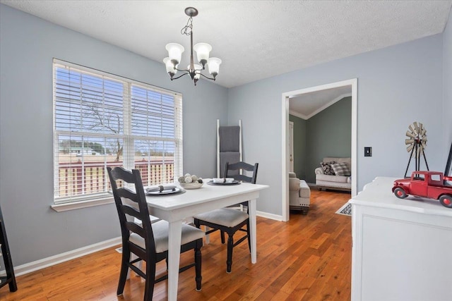 dining area featuring a healthy amount of sunlight, dark wood-type flooring, a textured ceiling, and a chandelier