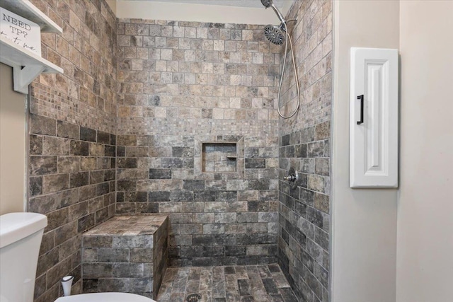 bathroom featuring a tile shower and toilet