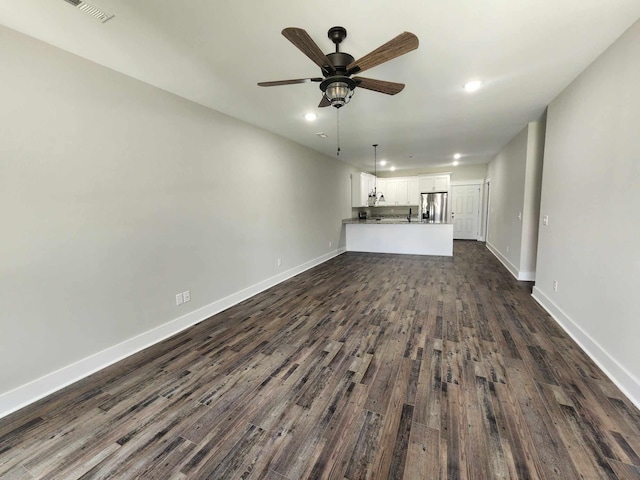 unfurnished living room featuring ceiling fan and dark wood-type flooring