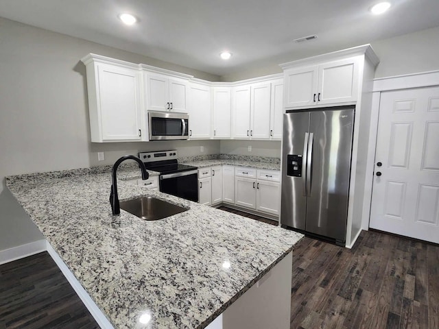 kitchen with kitchen peninsula, white cabinetry, sink, and stainless steel appliances