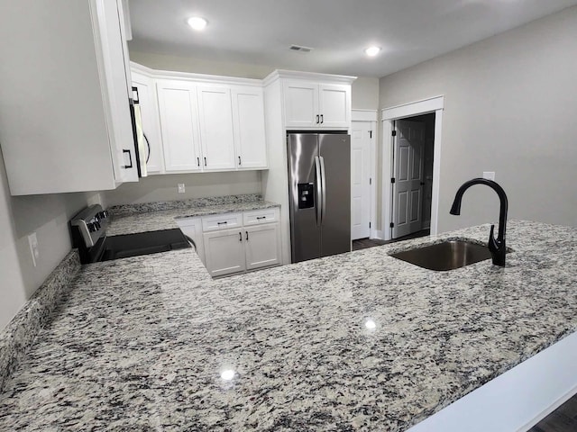 kitchen with white cabinets, stainless steel refrigerator with ice dispenser, and stove