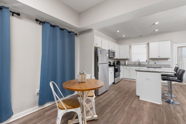 kitchen featuring sink, a center island, stainless steel appliances, a kitchen bar, and white cabinets