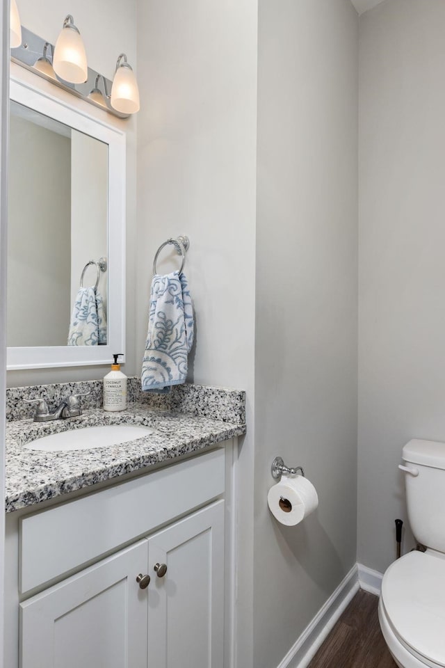 bathroom with hardwood / wood-style floors, vanity, and toilet