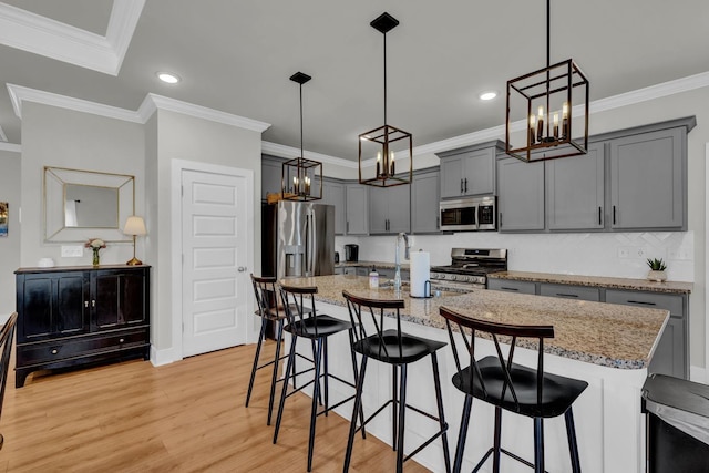  - kitchen featuring stainless steel appliances, a chandelier, a kitchen bar, light wood finished floors, and recessed lighting