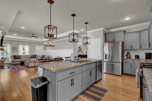  - kitchen with stainless steel appliances, a sink, gray cabinets, ornamental molding, and light stone countertops