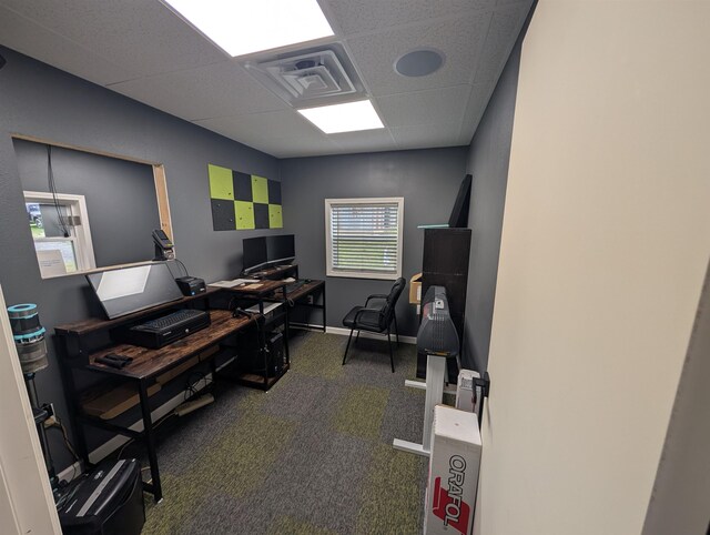 carpeted office space featuring baseboards, visible vents, and a paneled ceiling