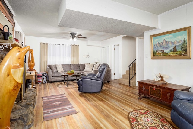  - living room with light wood-style floors, stairway, a ceiling fan, and a textured ceiling