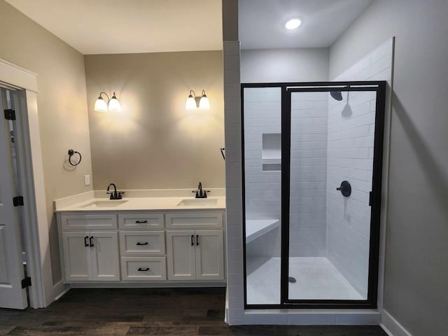 bathroom with hardwood / wood-style floors, vanity, and a shower with door