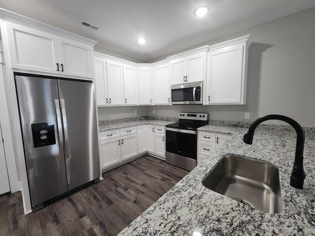 kitchen featuring white cabinets, stainless steel appliances, light stone countertops, and sink