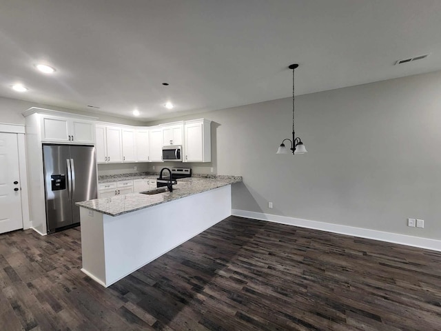 kitchen featuring white cabinets, hanging light fixtures, appliances with stainless steel finishes, light stone counters, and kitchen peninsula