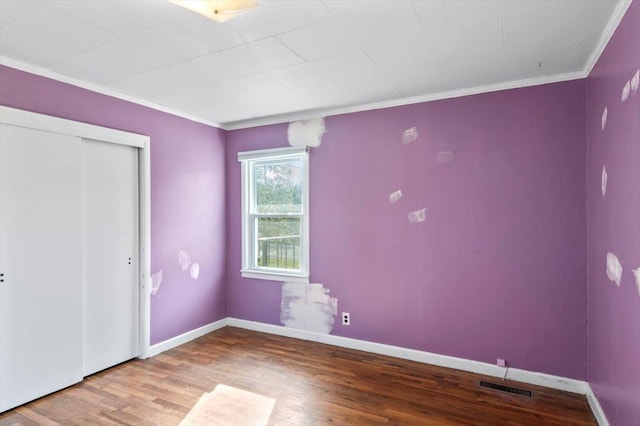 unfurnished bedroom with a closet, ornamental molding, and hardwood / wood-style flooring