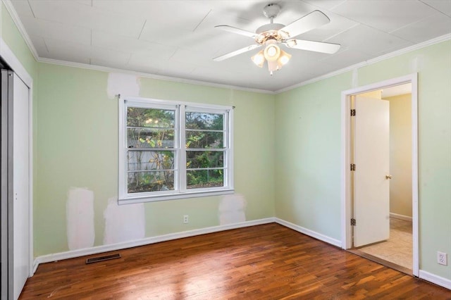 unfurnished bedroom featuring hardwood / wood-style floors, ceiling fan, crown molding, and a closet