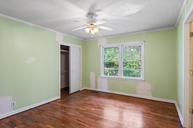 unfurnished bedroom with ceiling fan, crown molding, dark wood-type flooring, and a closet