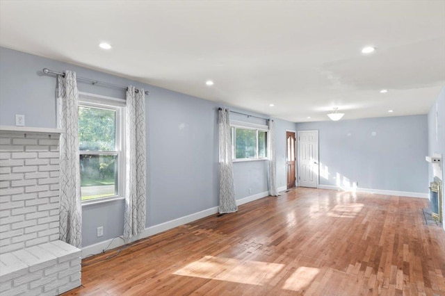 unfurnished living room with hardwood / wood-style floors and a brick fireplace