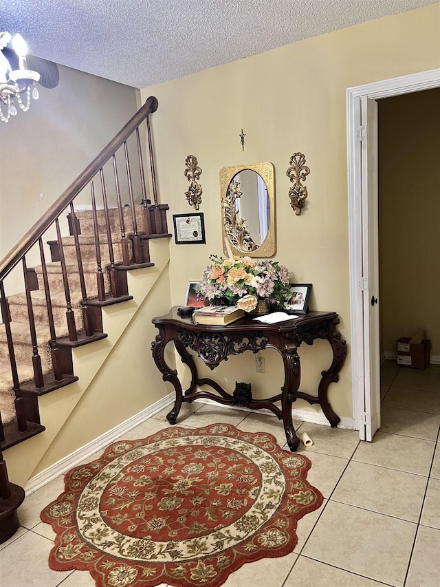  - staircase with tile patterned flooring, a chandelier, and a textured ceiling