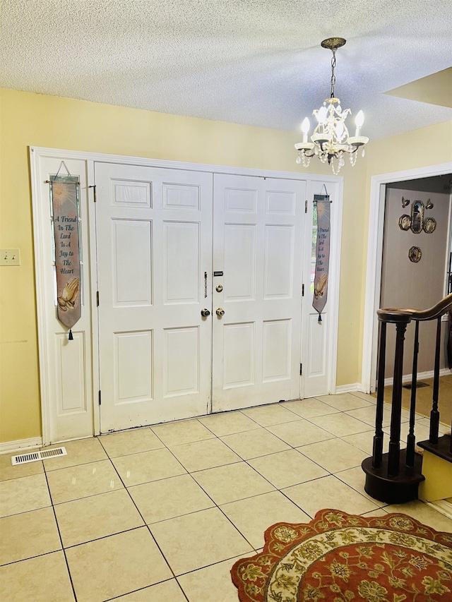 - foyer featuring a chandelier, light tile patterned floors, and a textured ceiling