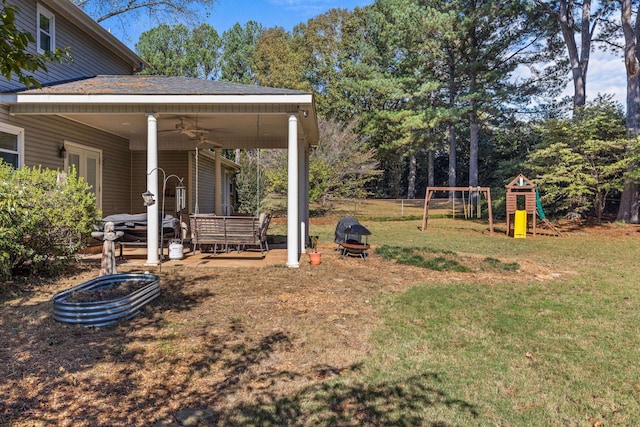 view of yard with a playground, ceiling fan, and an outdoor fire pit