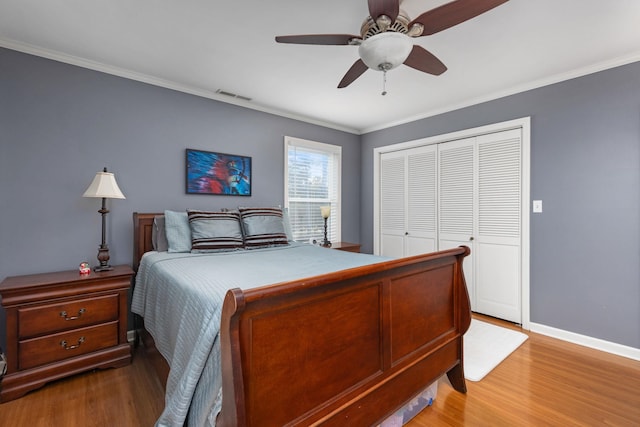 bedroom with hardwood / wood-style floors, a closet, ceiling fan, and crown molding