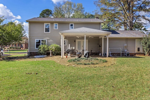 back of property with ceiling fan and a yard