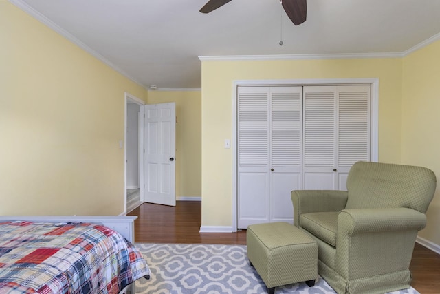 bedroom featuring dark wood-type flooring, ceiling fan, a closet, and crown molding