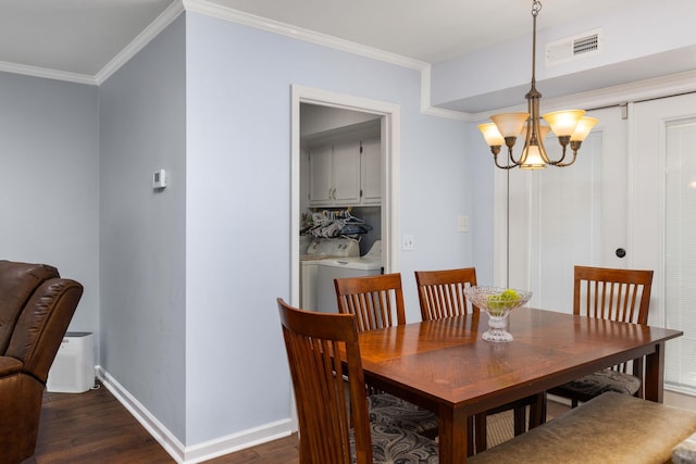 dining room featuring washer and dryer, dark hardwood / wood-style flooring, ornamental molding, and an inviting chandelier