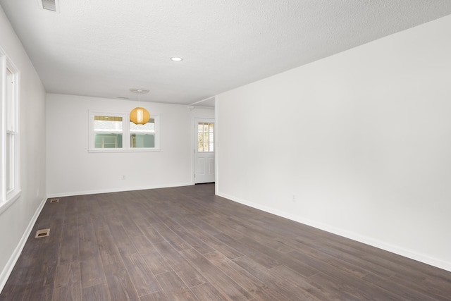 spare room featuring dark hardwood / wood-style flooring and a textured ceiling