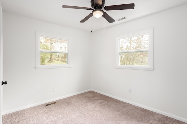 carpeted empty room featuring a wealth of natural light and ceiling fan