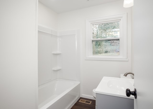 full bathroom featuring hardwood / wood-style flooring, shower / tub combination, vanity, and toilet