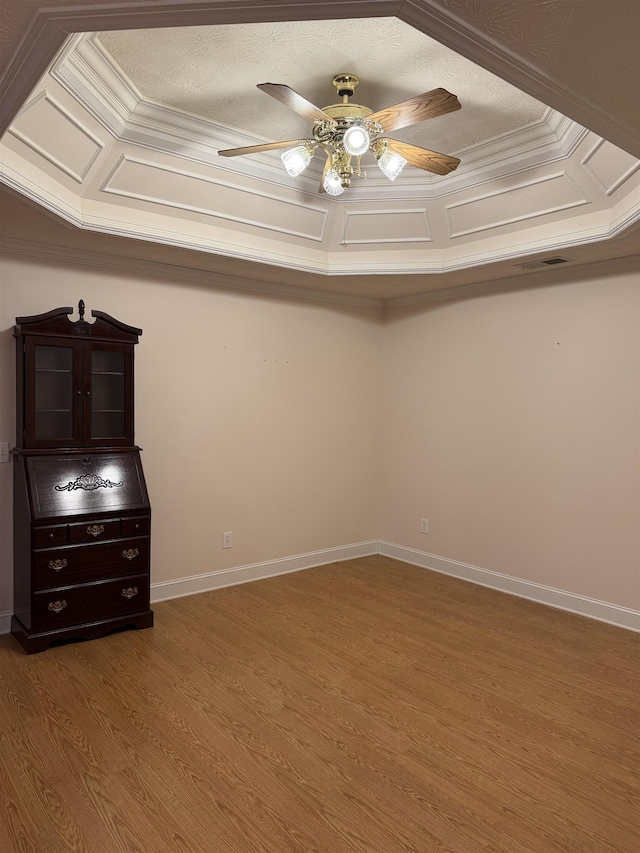 interior space with ceiling fan, wood-type flooring, ornamental molding, and a textured ceiling