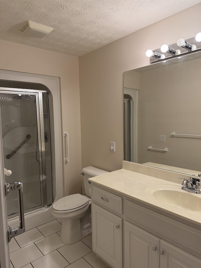 bathroom featuring an enclosed shower, vanity, a textured ceiling, tile patterned flooring, and toilet