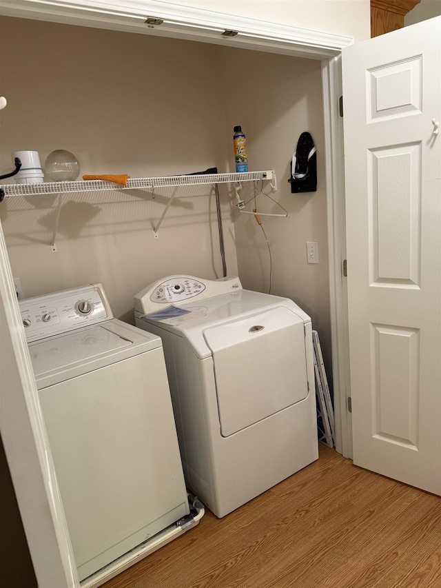 clothes washing area featuring washer and clothes dryer and light hardwood / wood-style floors