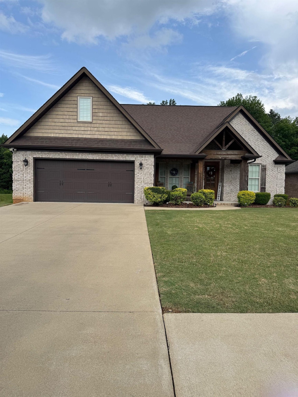  - view of front facade with brick siding, a front lawn, concrete driveway, and an attached garage
