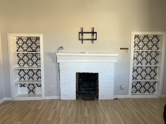 unfurnished living room featuring a fireplace, built in shelves, and hardwood / wood-style floors