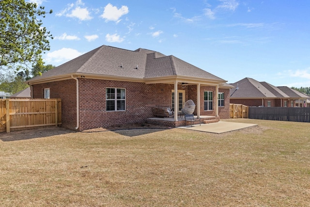 back of house featuring a patio, a fenced backyard, brick siding, a shingled roof, and a yard