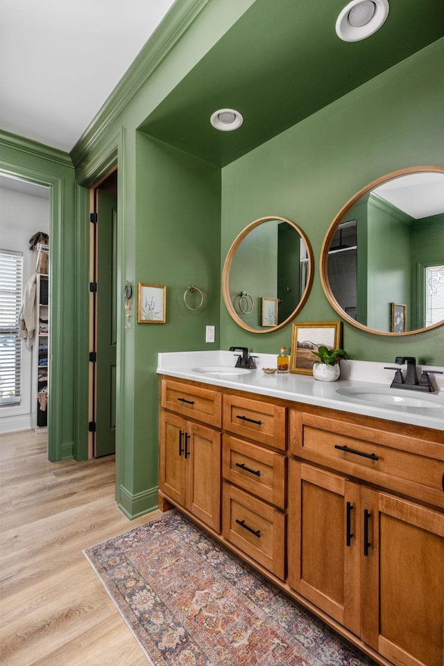 full bathroom featuring crown molding, a sink, wood finished floors, and a healthy amount of sunlight